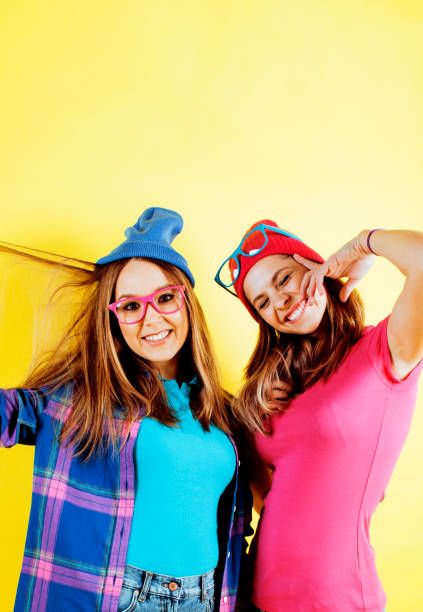 lifestyle people concept: two pretty stylish modern hipster teen girl having fun together, happy smiling making selfie close up on yellow background, diverse type of girls stock photo