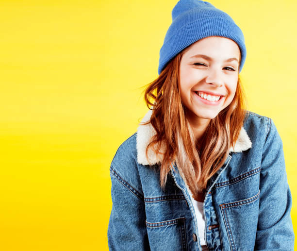 lifestyle people concept: pretty young school teenage girl having fun happy smiling on yellow background close up stock photo