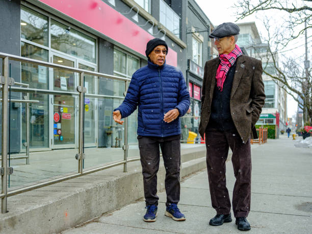 uomini anziani fuori per una passeggiata invernale in città - cold discussion outdoors snow foto e immagini stock