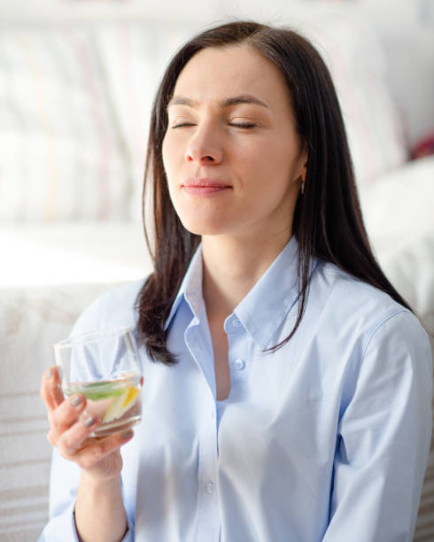 woman in blue shirt holding glass of water and smiling at home - salad food and drink food lettuce imagens e fotografias de stock