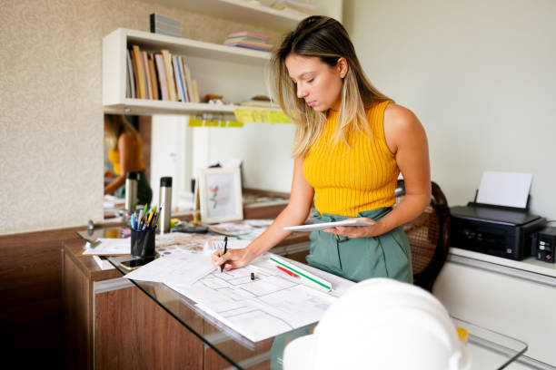 istock Woman architect office working with blueprints at her office 1372400690