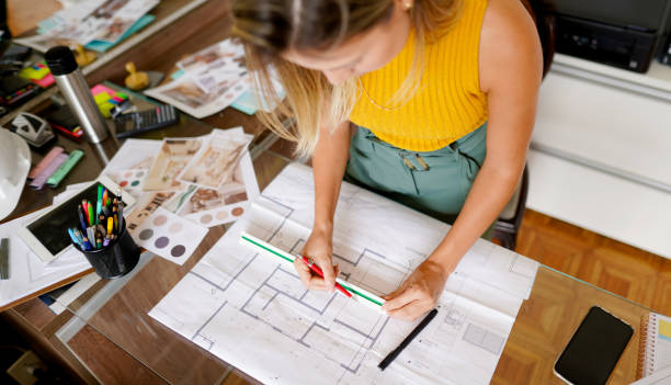 istock Female architect measuring blueprints at a table in her office 1372400701