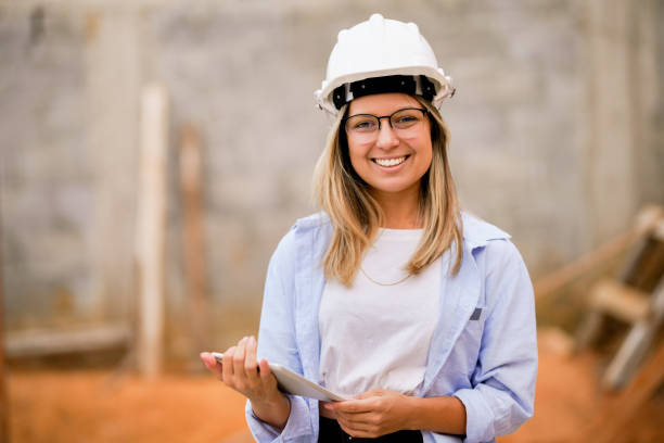 retrato de una hermosa mujer ingeniera en el sitio de construcción - architect women blueprint eyewear fotografías e imágenes de stock