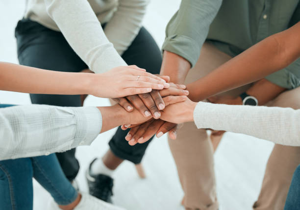 plan recadré d’un groupe méconnaissable de personnes assises ensemble et empilant leurs mains au milieu - inclusion photos et images de collection