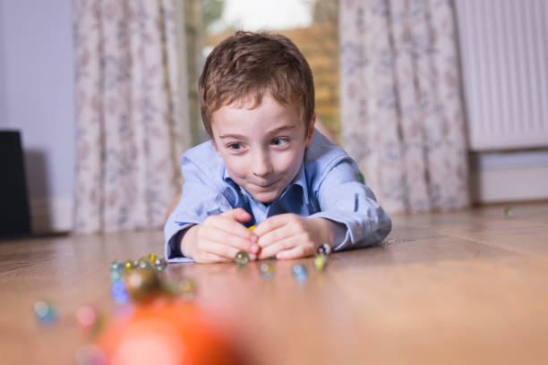 Boy of 7 on the lounge floor playing with his marbles.