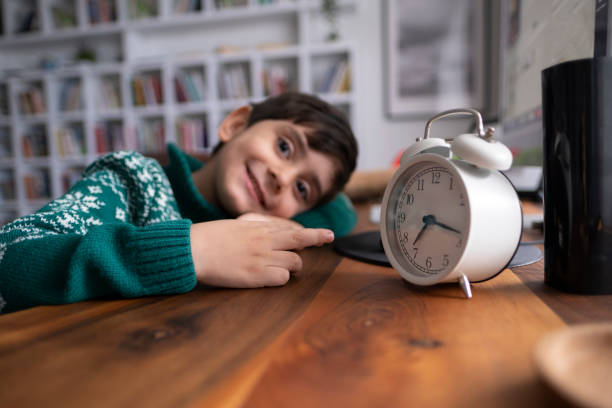 Joyful little boy with showing an alarm clock