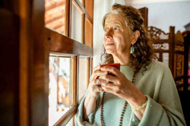 istock Senior woman deep in thought while drinking coffee by a window 1372406701