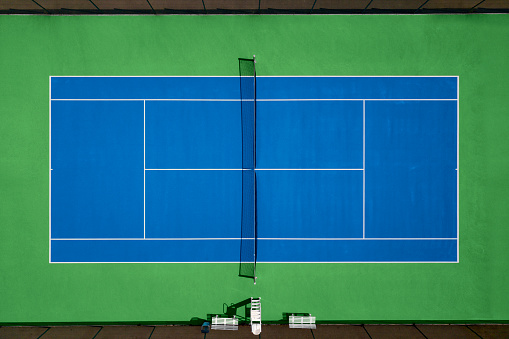 Yellow ball on floor behind paddle net in blue court outdoors. Man who playing padel tennis. Caucasian player sportsman hitting balls. Racquet sport game concept.