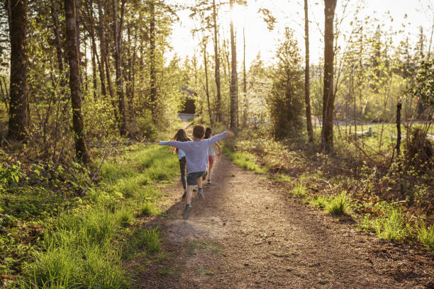 istock Carefree kids running down dirt path in forest 1372416089