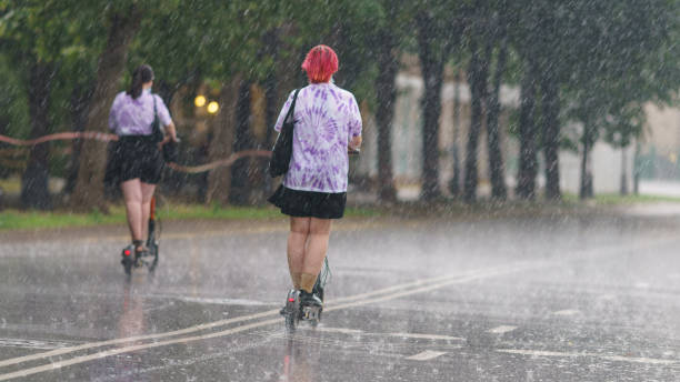 people ride motor scooter in the public park in rain - rain drenched men wet imagens e fotografias de stock