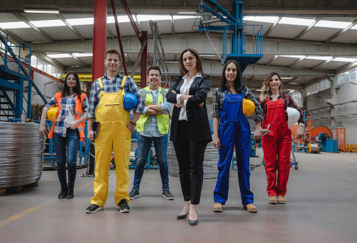 Portrait of distribution warehouse workers team working together and looking at camera in work overalls