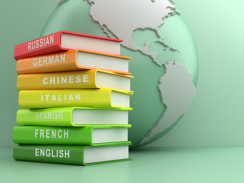 Multicolored foreign language books in front of a green globe. Learning new languages and translation concept