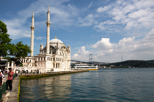 Istanbul, Turkey - June 08, 2021: People spending weekend and fishing in Ortakoy near beautiful mosque and Bosphorus in Istanbul.