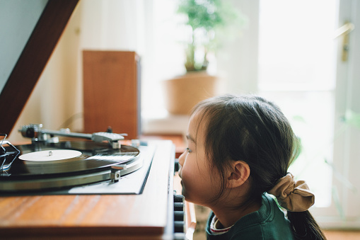 Asian little girl staring at his granddad's record player at home.
