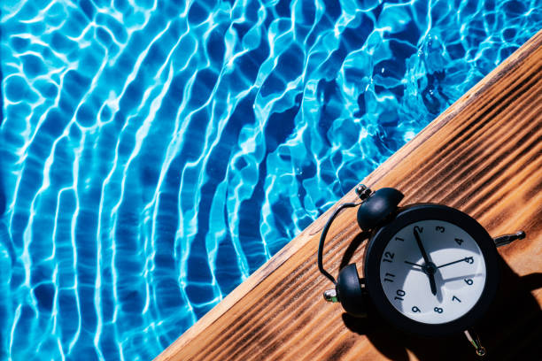 Wood sand board black alarm daily clock. Blue transparent reflect wave water surface ocean. Vacation summer. Adolescence stock photo