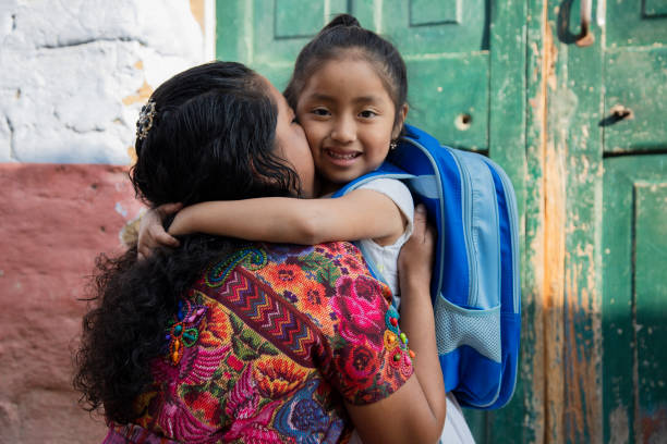 hispanische maya-mutter, die ihre kleine tochter umarmt, bereit für ihren ersten schultag-kleines mädchen mit ihrer mutter, die bereit ist, zur schule zu gehen- zurück zur schule in lateinamerika - lateinamerikaner oder hispanic stock-fotos und bilder