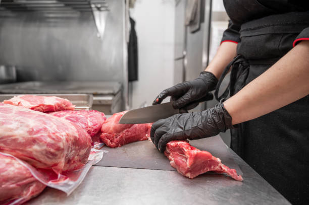 primer plano de carne cruda y mujer carnicero cortando carne con cuchillo. foto de alta calidad - carnicería fotografías e imágenes de stock