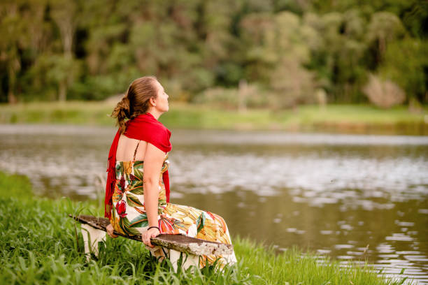 Young woman sitting with her eyes closed alone on a bench outside by a tranquil lake