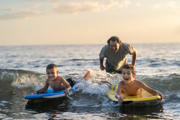 istock Dad teaching sons to body board 1372429458