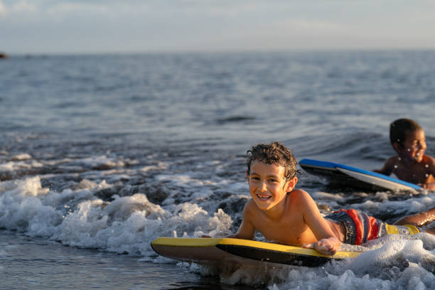 istock Elementary age boys having fun body boarding at the beach 1372429466