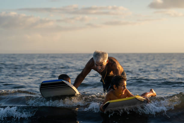 idoso ativo ensinando seus netos a body board - tropical climate family relaxation men - fotografias e filmes do acervo