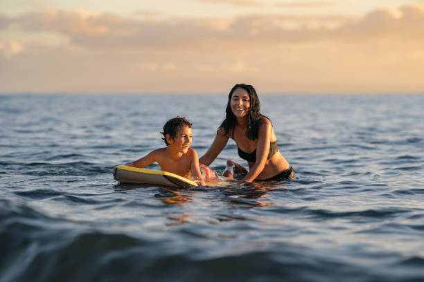 istock Loving mom helping her son body board at the beach 1372429478