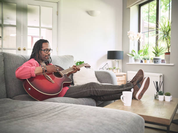 istock Shot of an elderly man having fun while playing the guitar on a sofa at home 1372429940