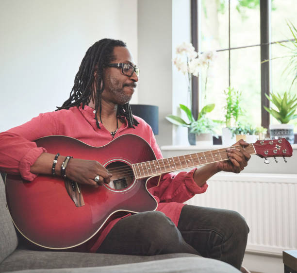 istock Shot of an elderly man having fun while playing the guitar on a sofa at home 1372429952