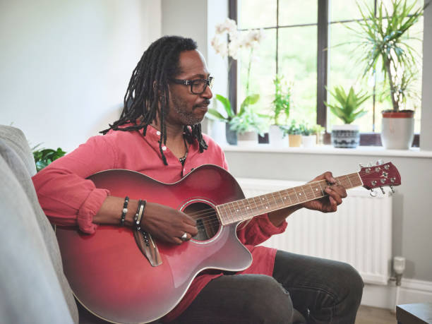 istock Shot of an elderly man having fun while playing the guitar on a sofa at home 1372429962