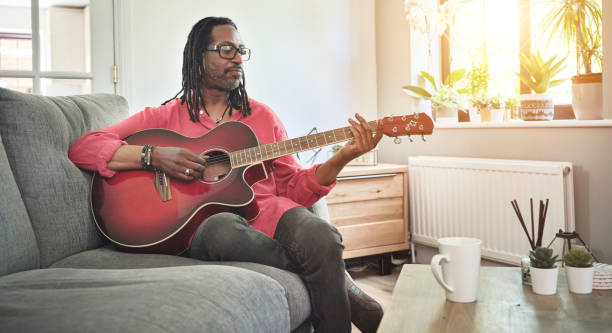 istock Shot of an elderly man having fun while playing the guitar on a sofa at home 1372429964