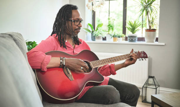 istock Shot of an elderly man having fun while playing the guitar on a sofa at home 1372430061