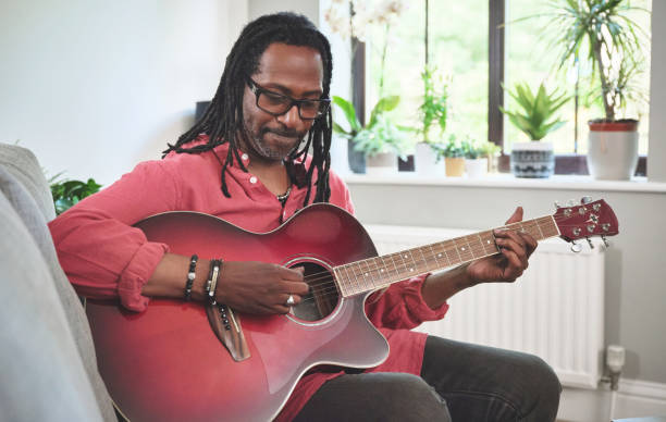 istock Shot of an elderly man having fun while playing the guitar on a sofa at home 1372430140