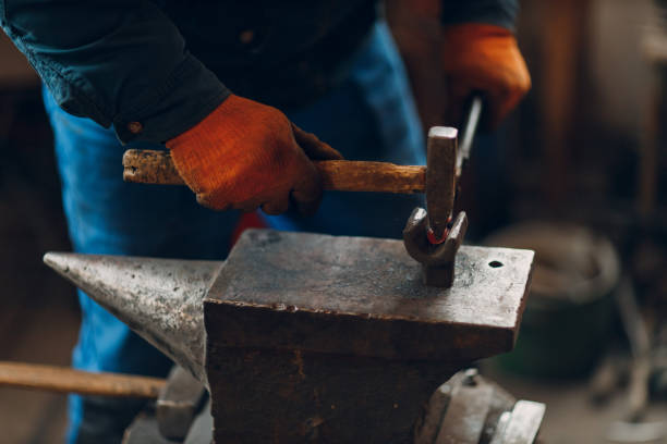 istock Blacksmith forges and makes metal detail with hammer and anvil at forge 1372441749