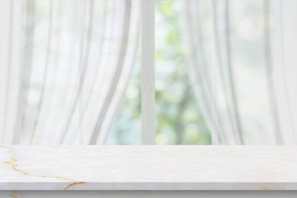 istock Marble table top on blur room interior with window curtain background 1372442060