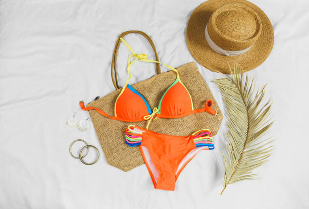 Orange swim suit, straw hat, straw bag, flip flops on white background. Summer concept, clothes for vacation, summer holidays Orange swim suit, straw hat, straw bag, flip flops on white background. Summer concept, clothes for vacation, summer holidays straw bag stock pictures, royalty-free photos & images