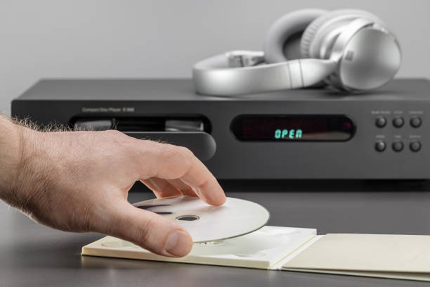 istock Hand of a man with a disc, an open tray of a CD player. Studio shot. 1372454647