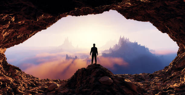 Dramatic View of Adventurous Man standing inrocky cave. Mountain Landscape Dramatic View of Adventurous Man standing inside a rocky and rugged cave looking over the Mountain Landscape. 3d Rendering. Colorful Sunrise Sky. Adventure Concept Artwork cave stock pictures, royalty-free photos & images