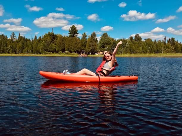 Cute happy teen girl with arms in air on kayak on a small lake. stock photo