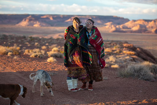 Cheerful Navajo sisters walking on the Arizona desert during a cold afternoon