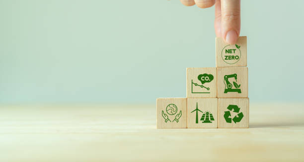 Net zero and carbon neutral concept. Net zero greenhouse gas emissions target. Climate neutral long term strategy. Putting wooden cubes with green net zero icon and save world icon on grey background. Net zero and carbon neutral concept. Net zero greenhouse gas emissions target. Climate neutral long term strategy. Putting wooden cubes with green net zero icon and save world icon on grey background. carbon neutrality stock pictures, royalty-free photos & images