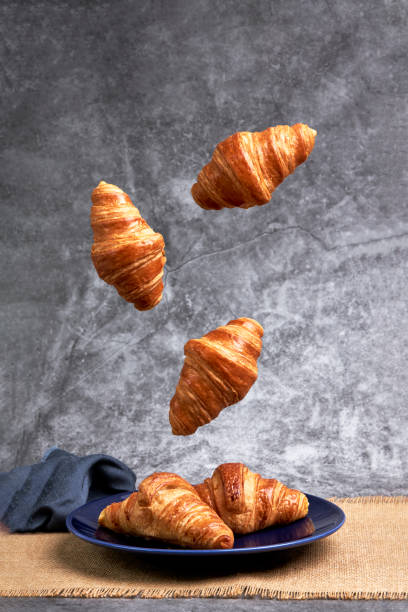 istock Group of croissants falling on a blue plate. Sweets and desserts 1372467169