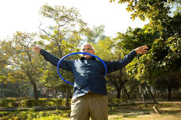 istock Senior man exercising with hula hoop at park 1372469950