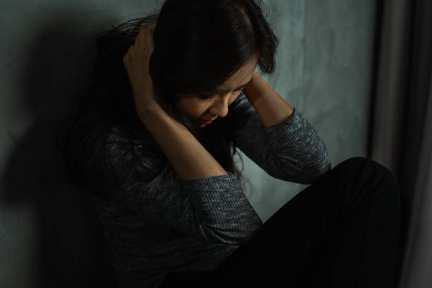 istock Young woman sitting sad, catch head, bow down, depression emotion, looking down in dark room, Portrait of young beautiful woman or female or girl sitting expression depression emotional alone 1372470469