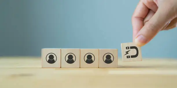 Photo of Customer retention concept. Inbound marketing strategy. Attracting potential customers.  Hand puts wooden cubes with magnet attracts customer icons on beautiful grey background and copy space. Loyalty