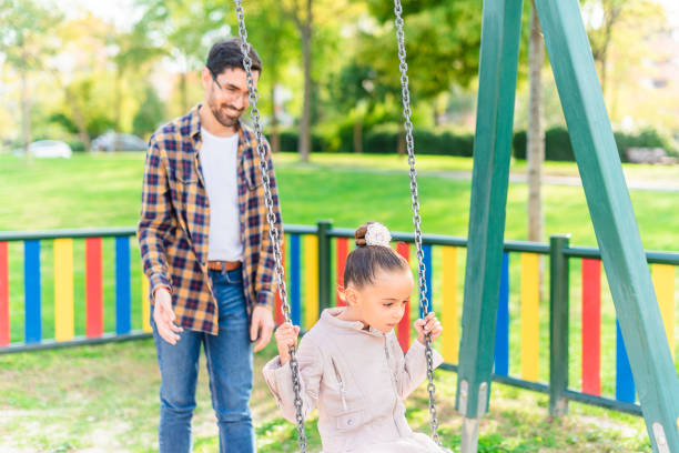 istock A young man playing with his adopted daughter on swing 1372472826