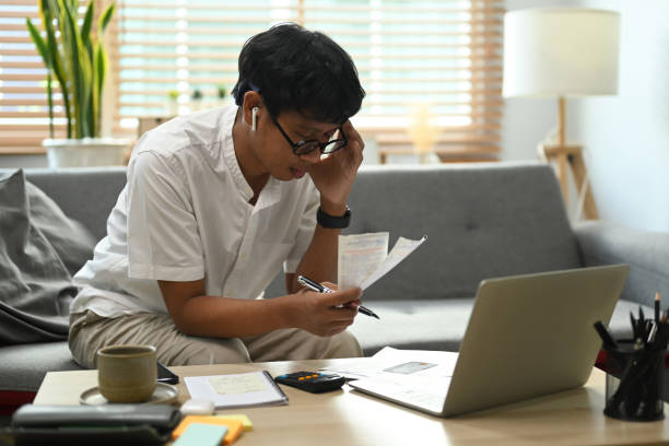istock Serious asian man using laptop computer and calculating household expenses. 1372480679