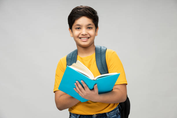 foto eines schuljungen mit gelbem t-shirt-rucksack im hintergrund, stockfoto - child reading education book stock-fotos und bilder