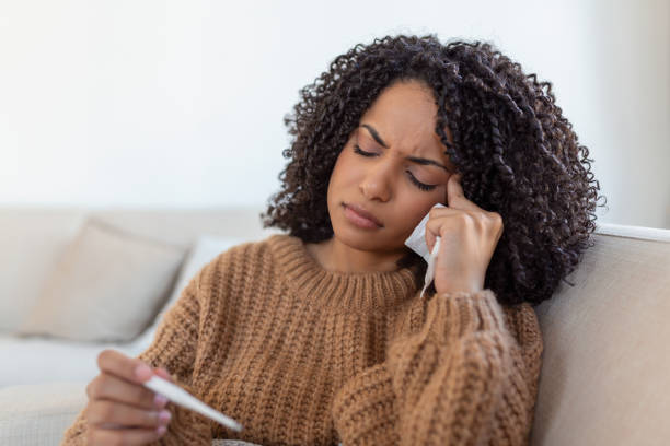 istock Sickness, seasonal virus problem concept. Woman being sick having flu lying on bed looking at temperature on thermometer. Sick woman lying in bed with high fever. Cold flu coronavirus, covid19 1372482039