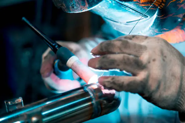 TIG welder welds elbow to polished stainless steel pipe