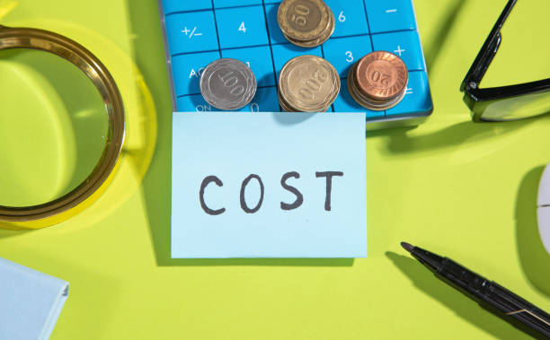 istock Text Cost in sticky note with a calculator, coins, marker. 1372488144